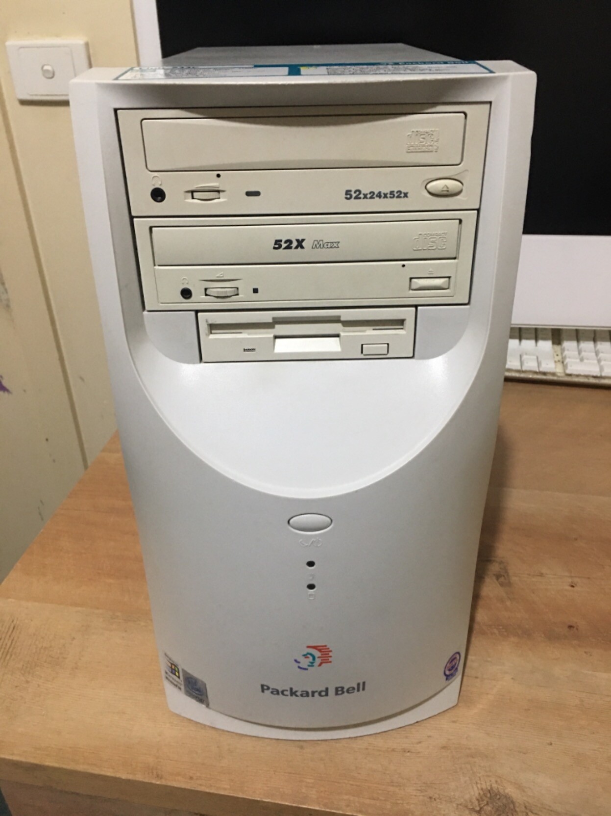 The front of the PC on my desk in front of my iMac. It has two CD drives and a floppy disk drive. The PC is a white colour.